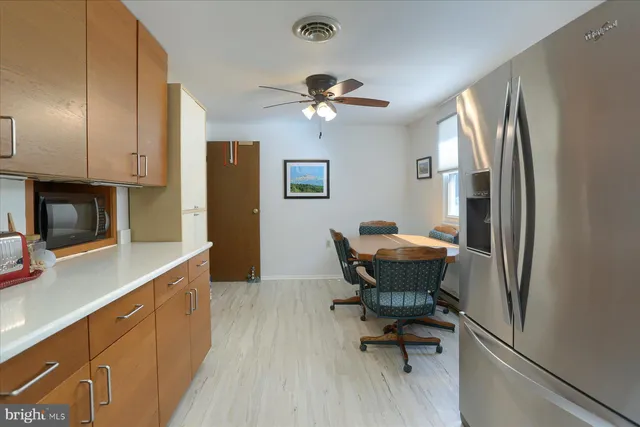 a view of a kitchen with dining area a sink a refrigerator and wooden floor