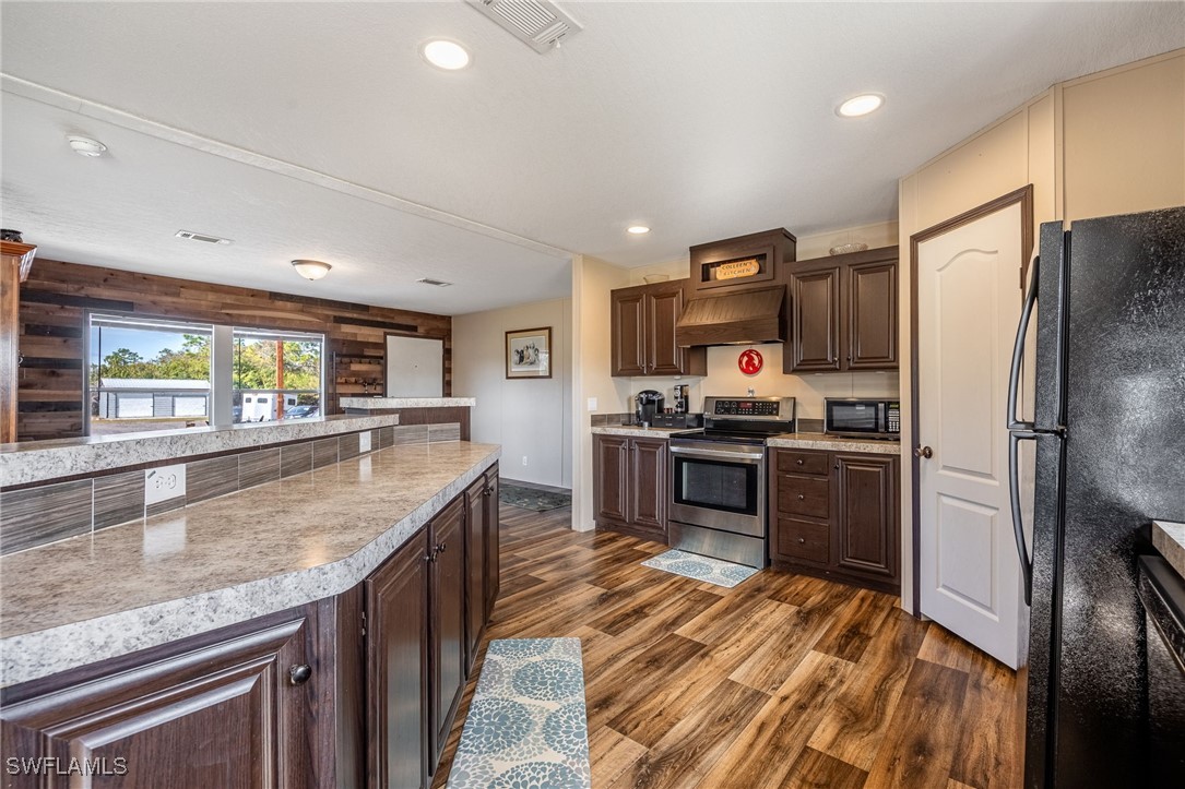 10491 Deal Road North Fort Myers, FL 33917 - Photo 13 of 48 a kitchen with stainless steel appliances granite countertop a refrigerator a stove and a sink with wooden floors