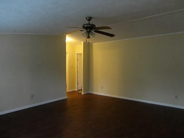 a view of a room with wooden floor and a ceiling fan