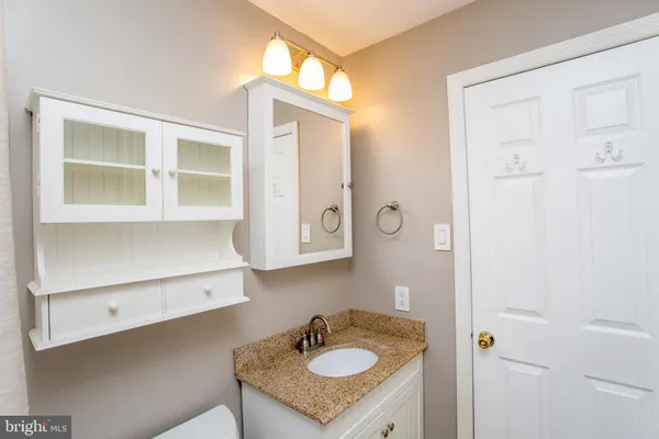 a bathroom with a granite countertop sink a mirror and a shower