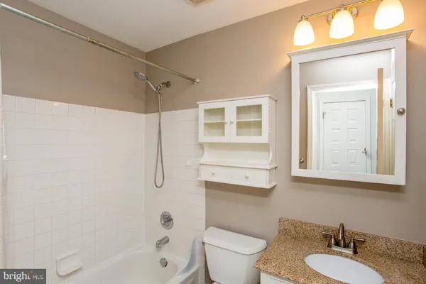 a bathroom with a granite countertop sink toilet a mirror and shower