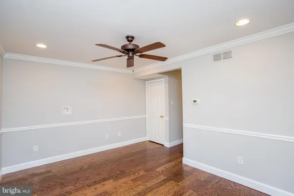 an empty room with wooden floor and ceiling fan
