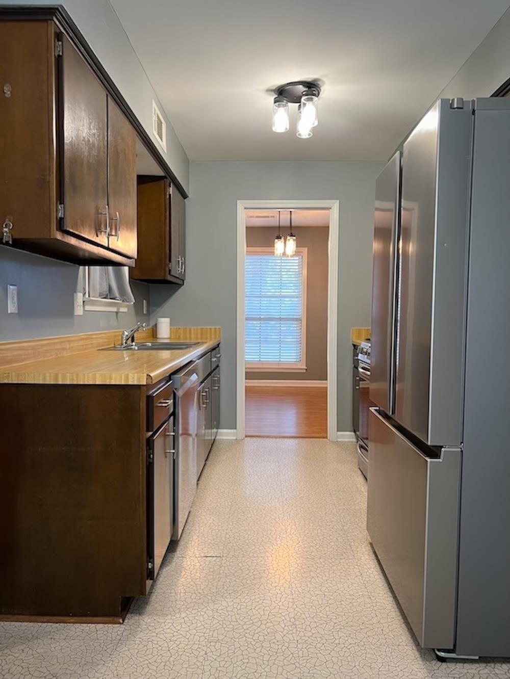 7935 Memphis Arlington Road Bartlett, TN 38133 - Photo 2 of 20 Galley kitchen featuring dark wood cabinetry, light-toned countertops, and stainless steel appliances