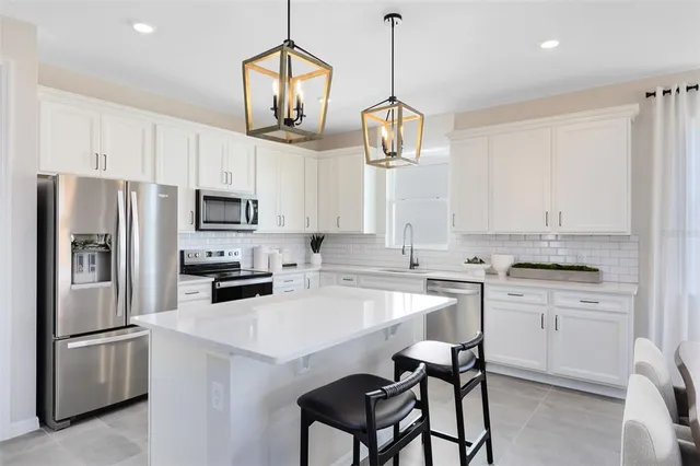 a kitchen with stainless steel appliances kitchen island granite countertop a refrigerator a stove a oven a sink a island a dining table and chairs