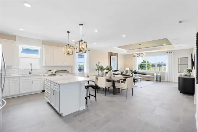 a kitchen with stainless steel appliances a stove a sink a refrigerator a center island a stove and white cabinets