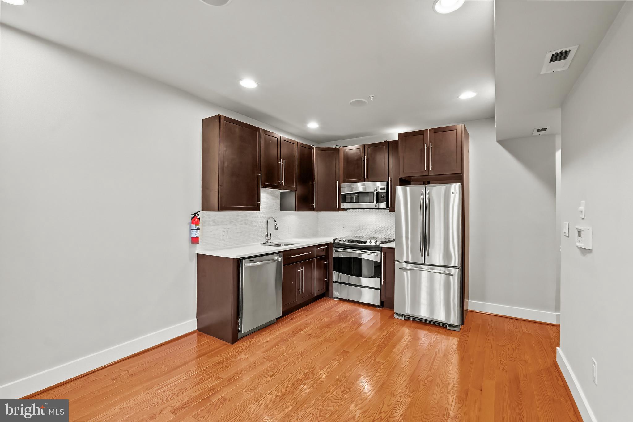 2616 Garfield Street Northwest, Unit 1 Washington, DC 20008 - Photo 2 of 22 a kitchen with granite countertop a refrigerator and a stove top oven