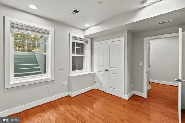 a view of an empty room with wooden floor and windows