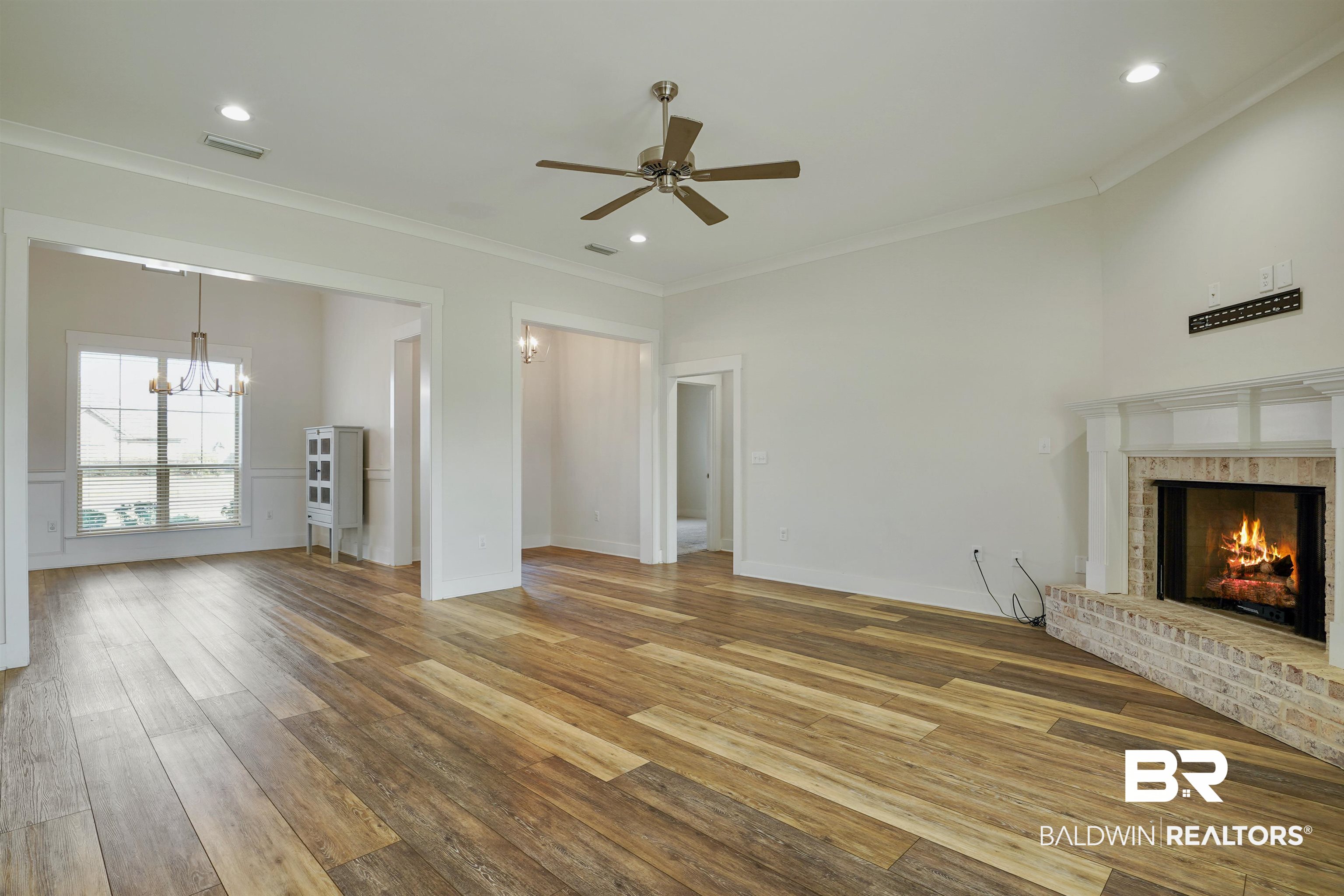 7090 Rocky Rd Loop Gulf Shores, AL 36542 - Photo 6 of 34 Unfurnished living room with a brick fireplace, wood finished floors, visible vents, and crown molding