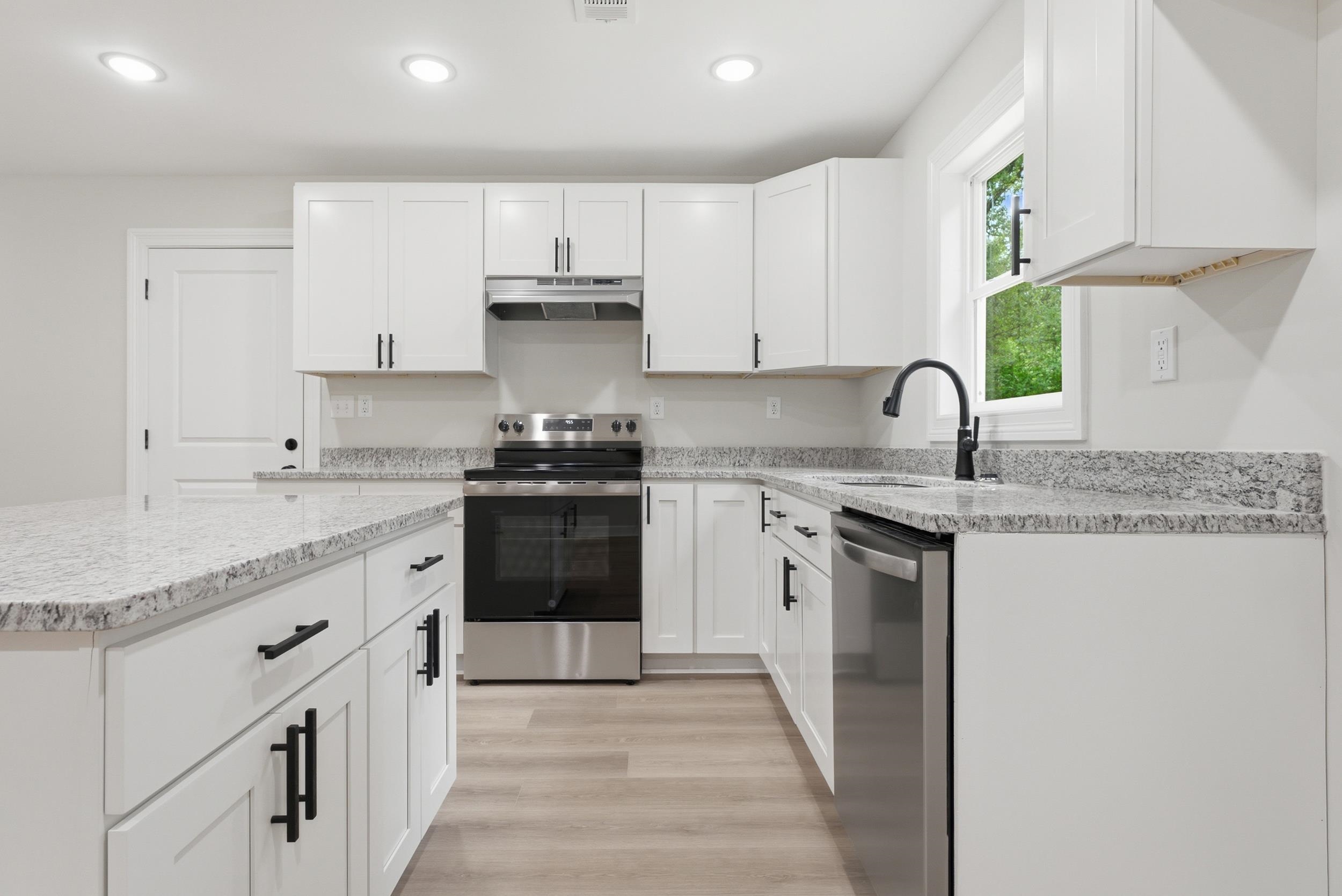 4683 Belmont Road Hernando, MS 38632 - Photo 11 of 21 Contemporary kitchen featuring white cabinetry with black hardware, stainless steel appliances, speckled stone countertops, wood-finish flooring, and recessed lighting