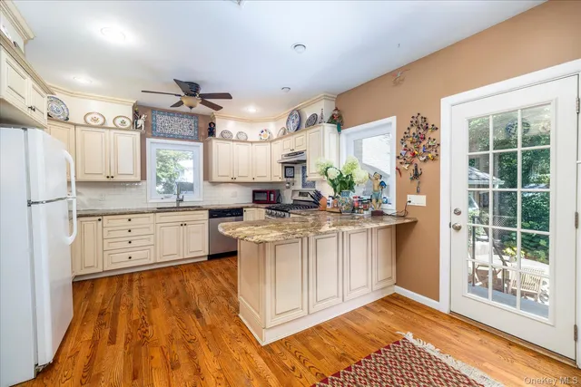 a kitchen with kitchen island granite countertop a stove a sink and white cabinets with wooden floor