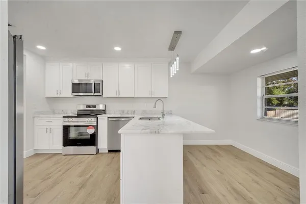 a kitchen with stainless steel appliances granite countertop a sink dishwasher a stove and a refrigerator with wooden floor