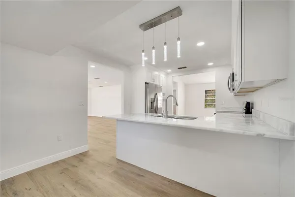 an empty room with wooden floor and kitchen view