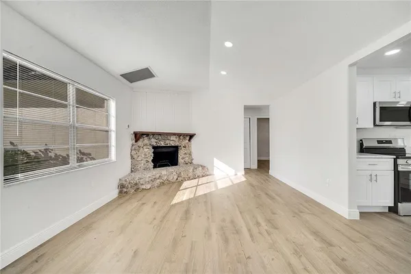 a view of a livingroom with wooden floor and a fireplace