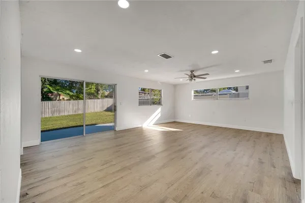 a view of empty room with wooden floor and windows