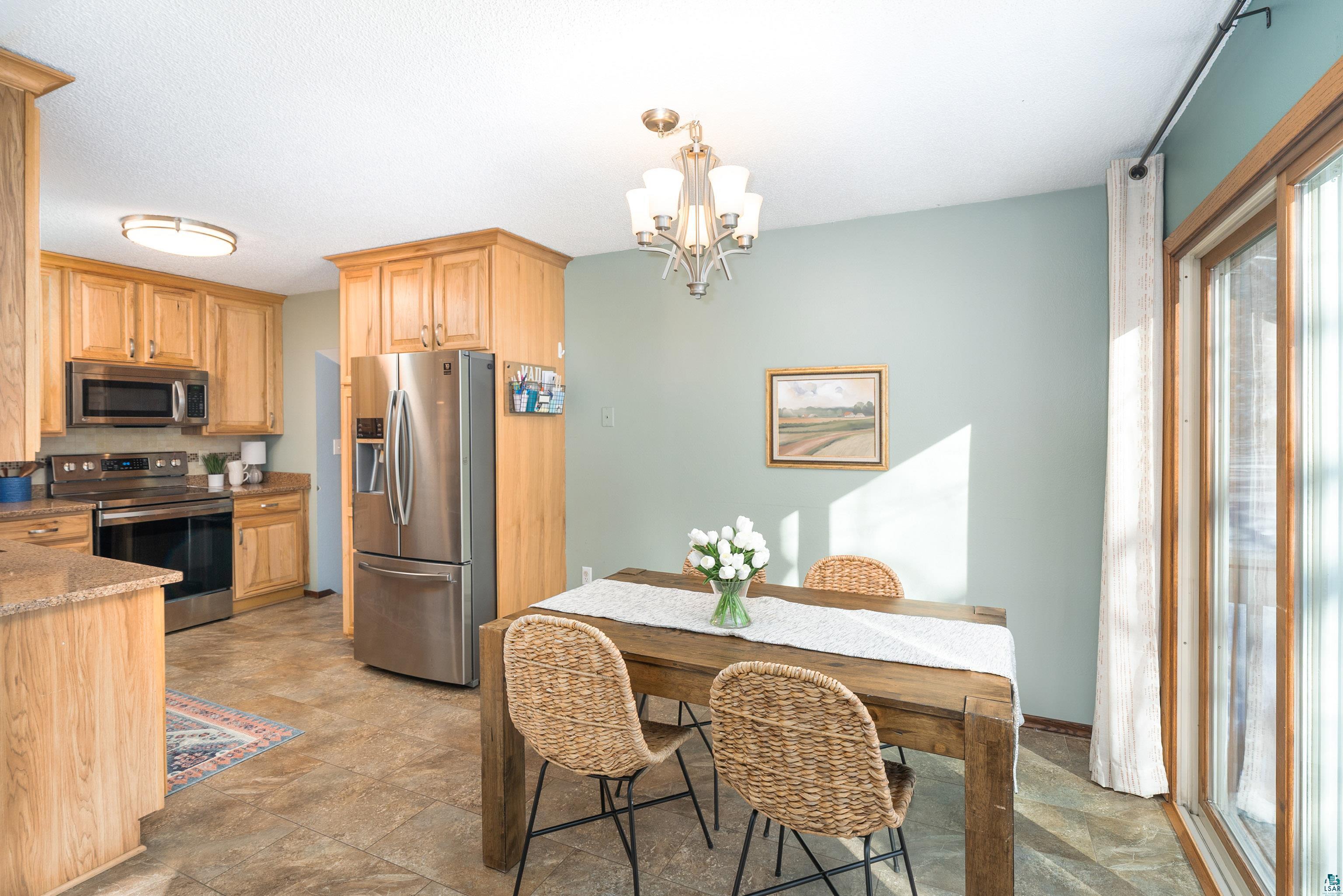 5947 East St Louis River Road Proctor, MN 55810 - Photo 11 of 47 Kitchen with stainless steel appliances, a chandelier, light wood finish cabinetry, stone finish floors, and light stone countertops