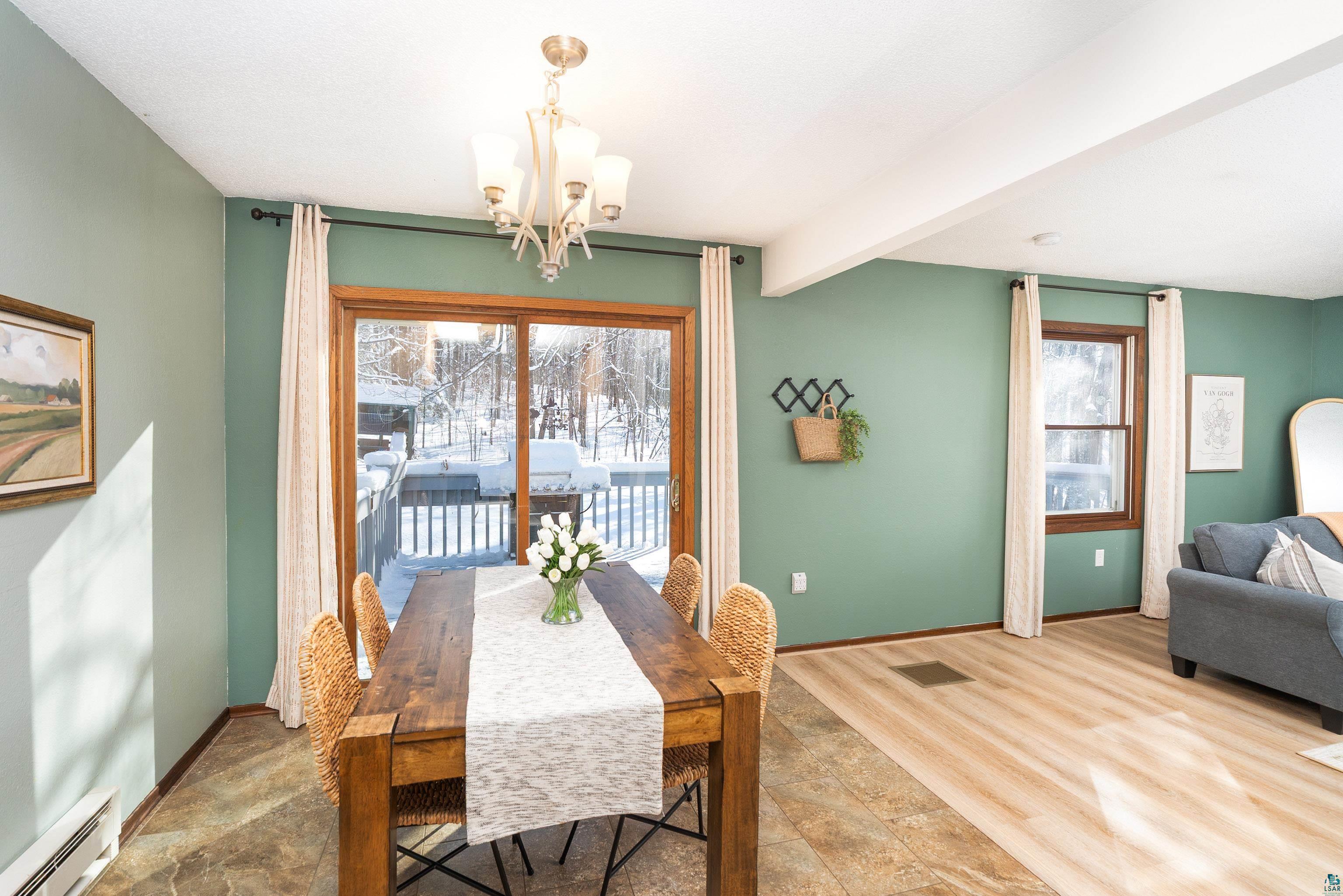 5947 East St Louis River Road Proctor, MN 55810 - Photo 13 of 47 Dining area featuring a chandelier, baseboard heating, beamed ceiling, and wood finished floors