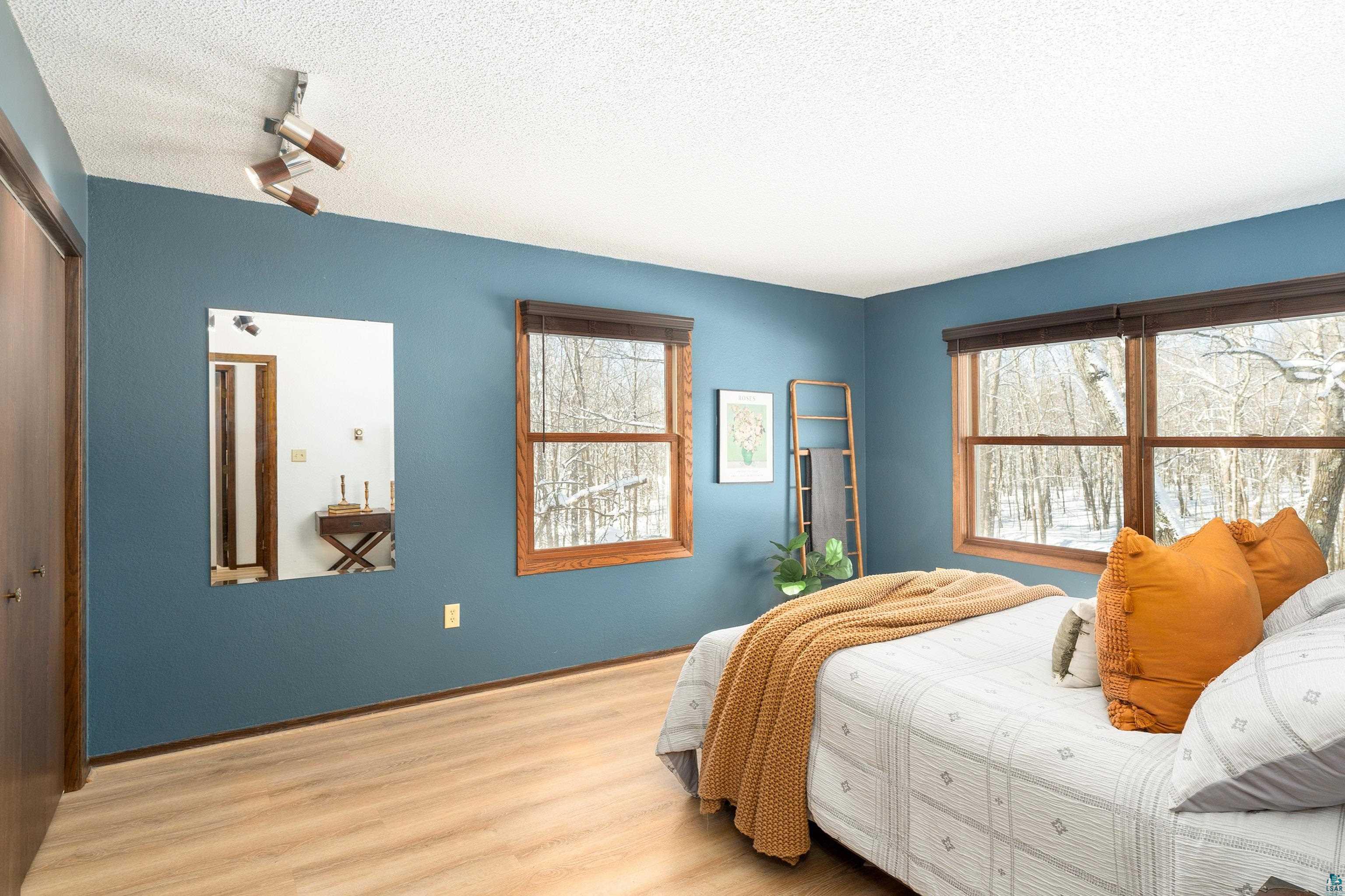 5947 East St Louis River Road Proctor, MN 55810 - Photo 17 of 47 Bedroom with light wood-style flooring, a textured ceiling, a closet, and track lighting