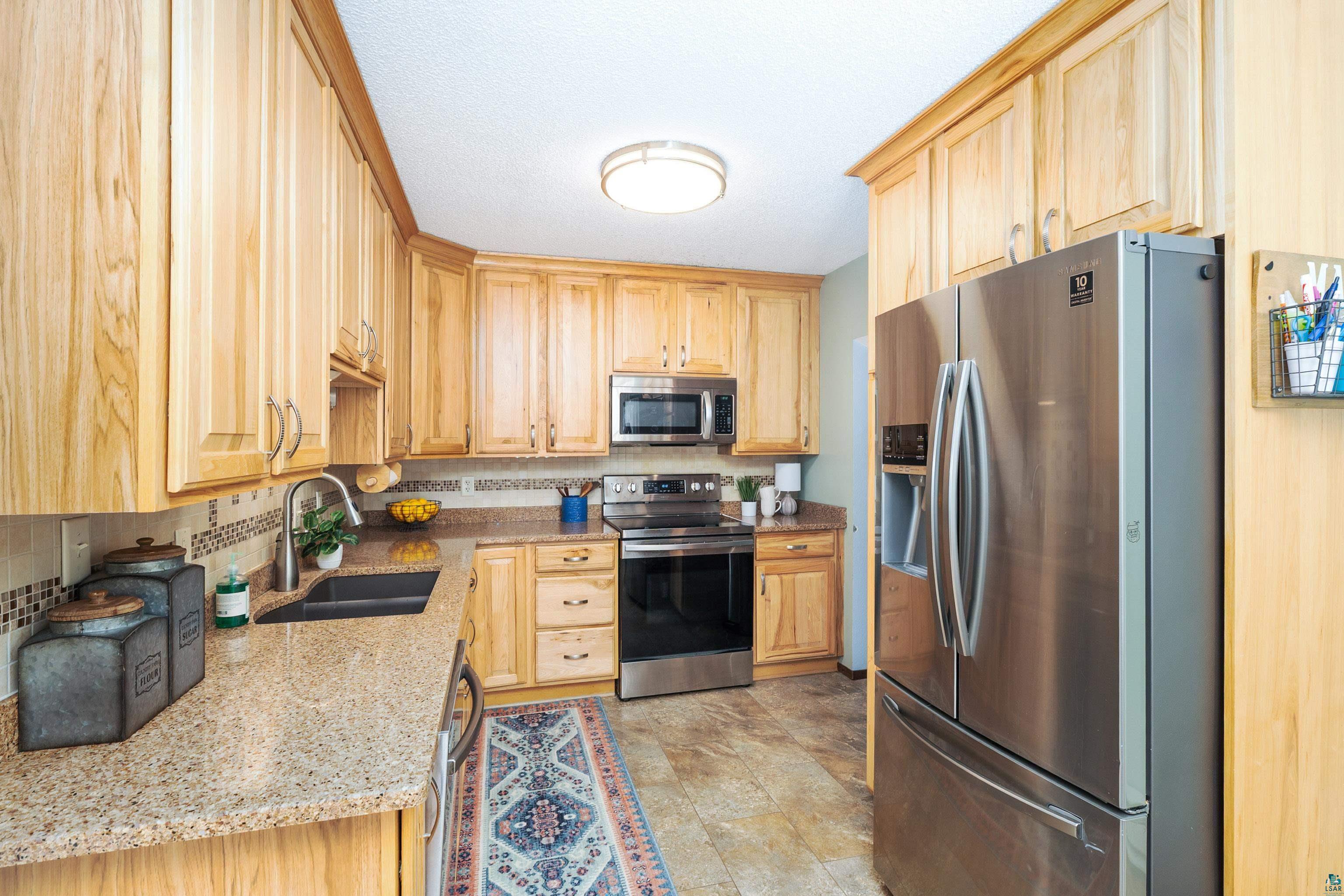 5947 East St Louis River Road Proctor, MN 55810 - Photo 10 of 47 Kitchen featuring stainless steel appliances, light wood finish cabinetry, backsplash, and light stone counters