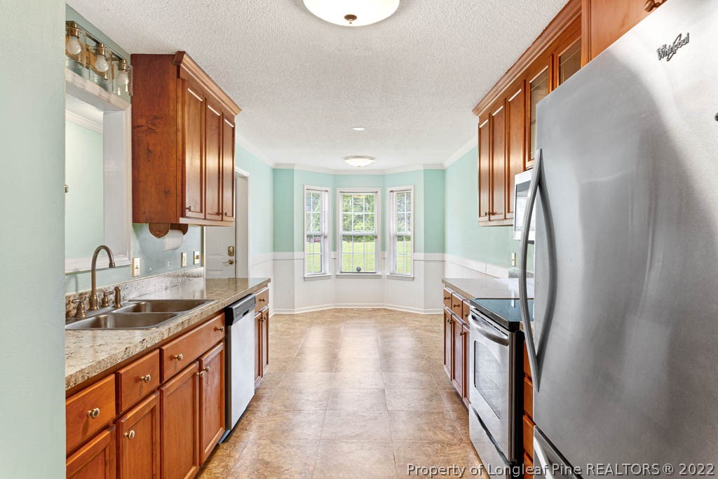 495 Sawyer Road Cameron, NC 28326 - Photo 9 of 33 a kitchen with stainless steel appliances granite countertop a sink stove and a refrigerator