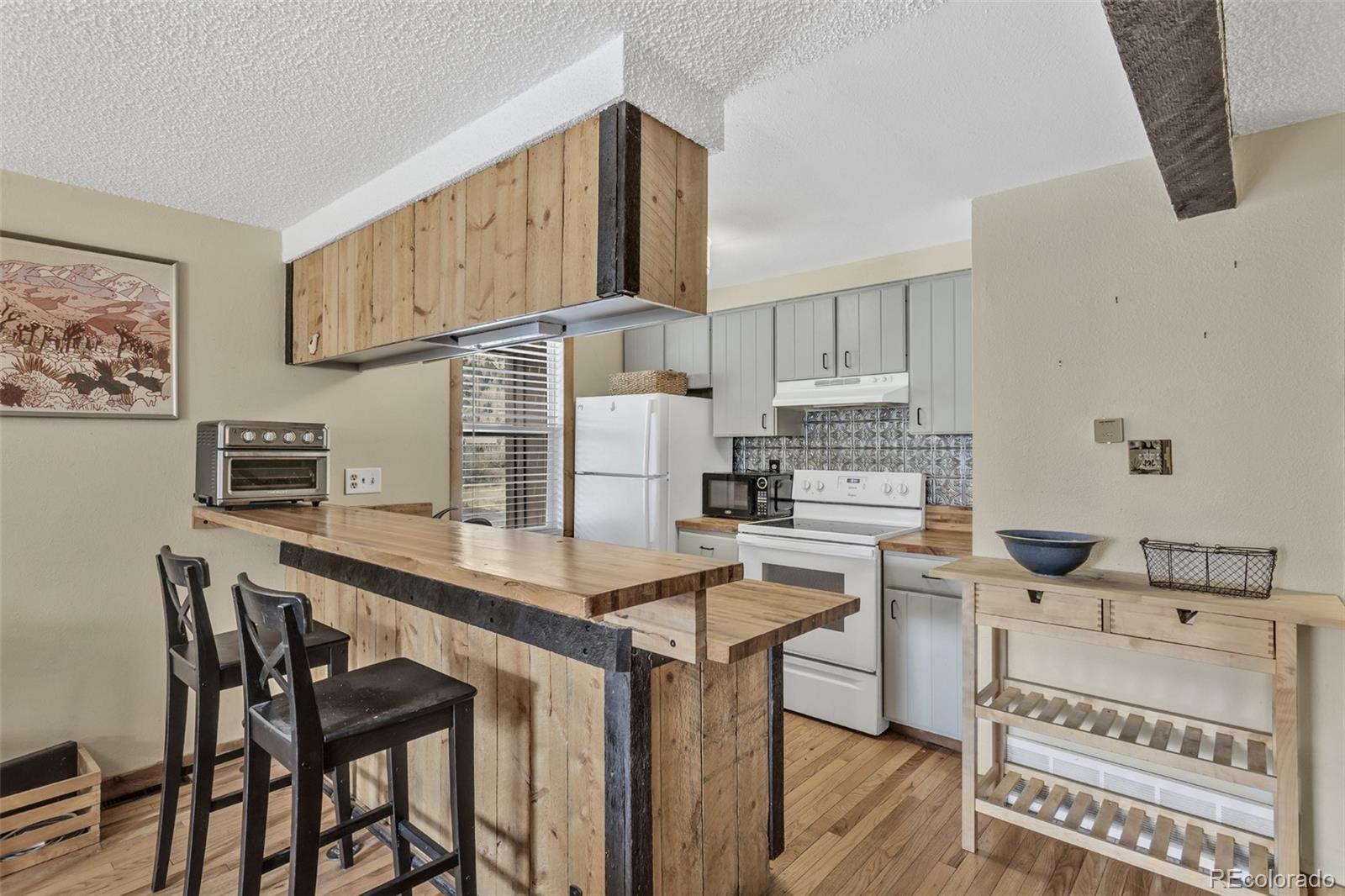 1450 Marion Street Georgetown, CO 80444 - Photo 4 of 25 a kitchen with stainless steel appliances kitchen island a table chairs in it and white cabinets