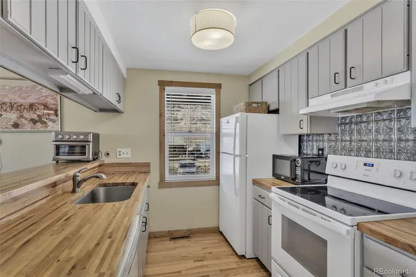 a kitchen with granite countertop a sink a stove and refrigerator