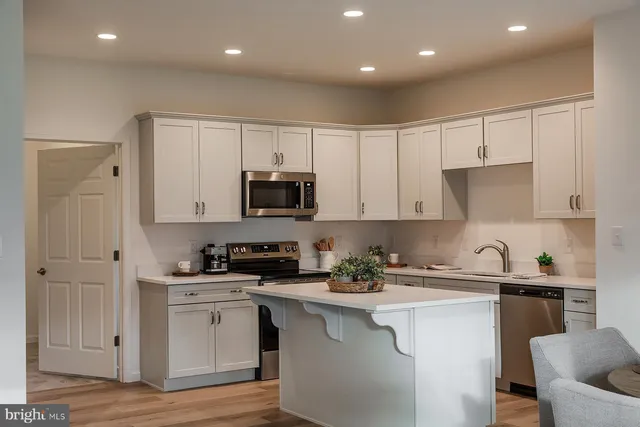 a kitchen with stainless steel appliances kitchen island granite countertop a sink stove and refrigerator