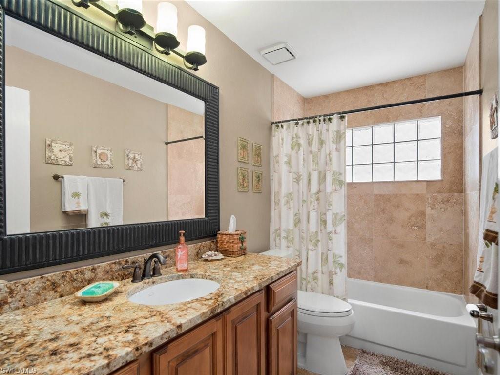 2088 Piccadilly Circus Naples, FL 34112 - Photo 18 of 29 a bathroom with a granite countertop sink a toilet a mirror a bathtub and shower