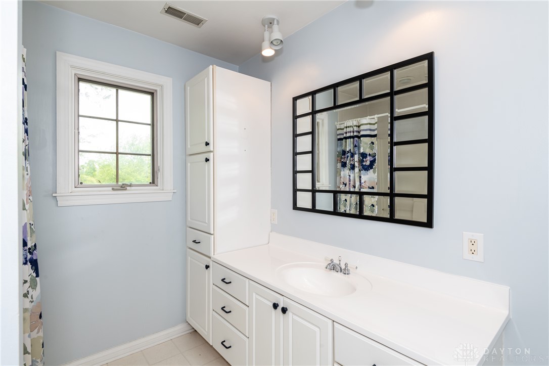 9981 Ridge Acres Lane Englewood, OH 45322 - Photo 32 of 73 This bathroom features ample storage, a window, and a sleek vanity with a mirror.