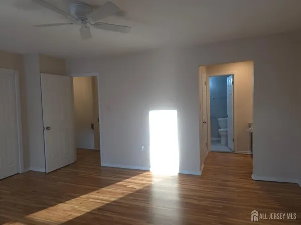 a view of an empty room with wooden floor and closet