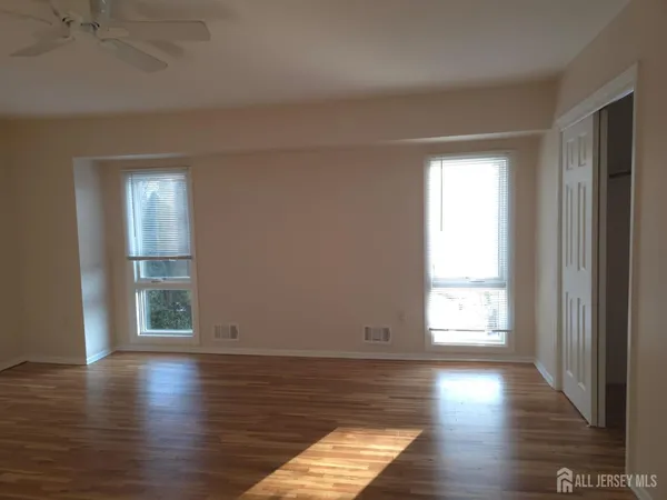 an empty room with wooden floor and windows