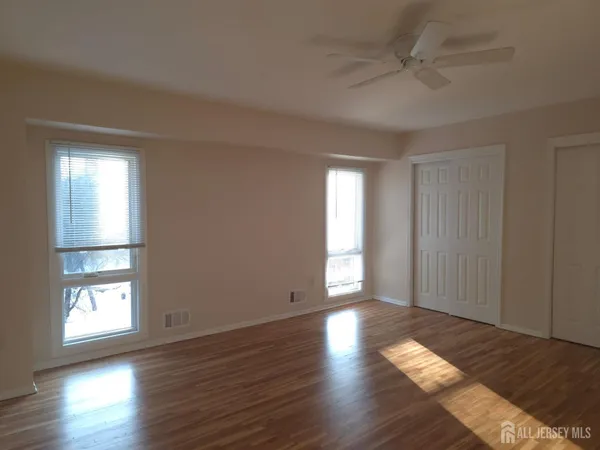 an empty room with wooden floor and windows