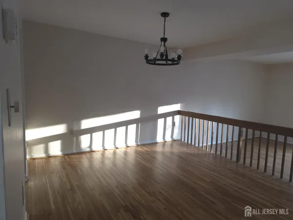 a view of a hallway with wooden floor and chandelier