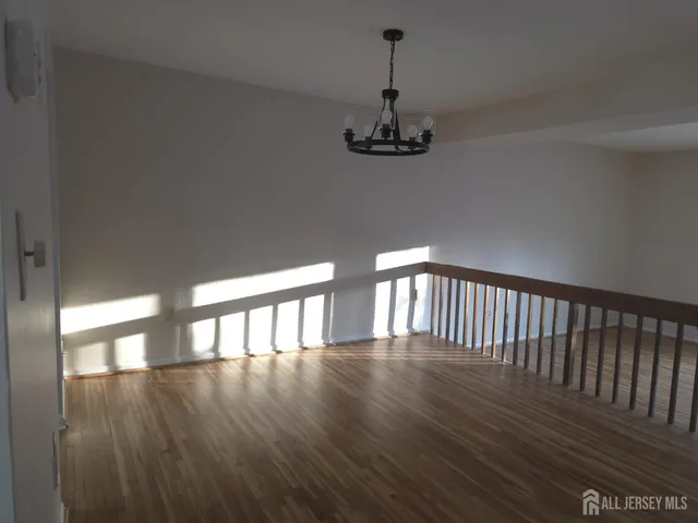 a view of a hallway with wooden floor and chandelier