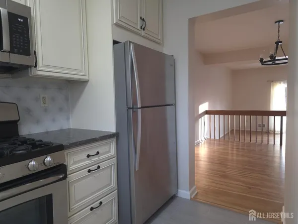 a kitchen with granite countertop a refrigerator stove and cabinets