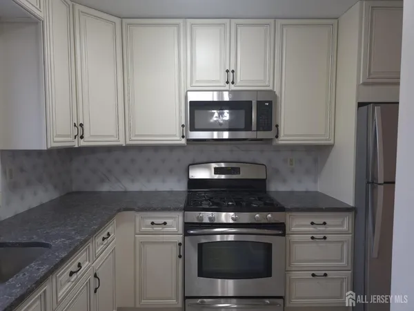 a kitchen with granite countertop white cabinets and stainless steel appliances