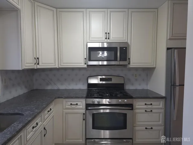a kitchen with granite countertop white cabinets and stainless steel appliances