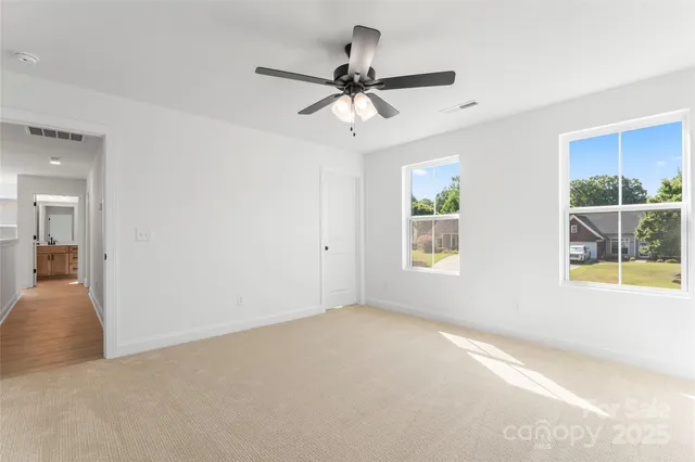 an empty room with windows and ceiling fan