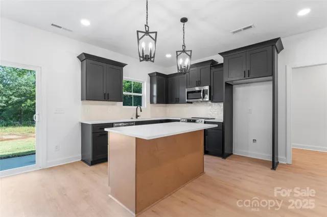 a large kitchen with stainless steel appliances granite countertop a sink a stove and a refrigerator