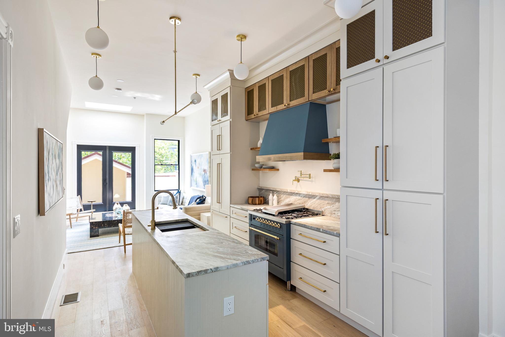 a kitchen that has a lot of white cabinets and stainless steel appliances