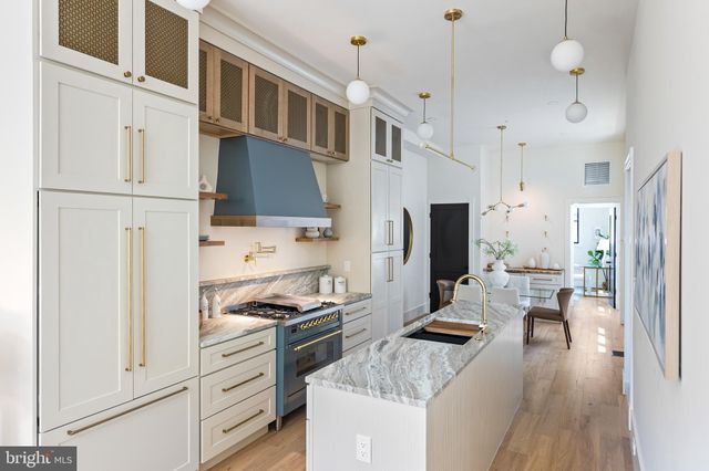 a kitchen with stainless steel appliances kitchen island granite countertop a refrigerator a stove and white cabinets with wooden floor