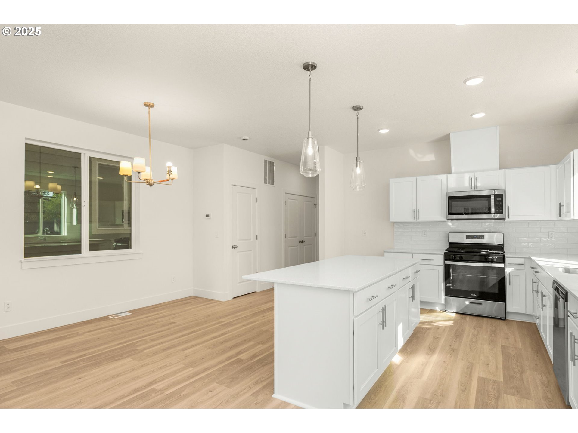 18933 Southwest Hazelwood Lane, Unit L9 Beaverton, OR 97078 - Photo 11 of 29 a kitchen with stainless steel appliances kitchen island granite countertop a sink a stove a refrigerator and white cabinets with wooden floor