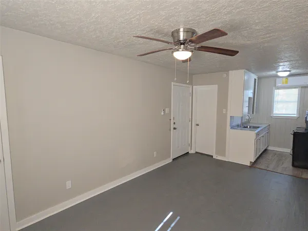 an empty room with a chandelier fan and windows