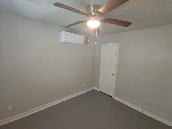 an empty room with a fan & a window