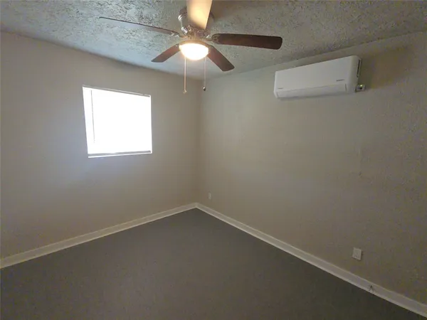 an empty room with a window and a fan