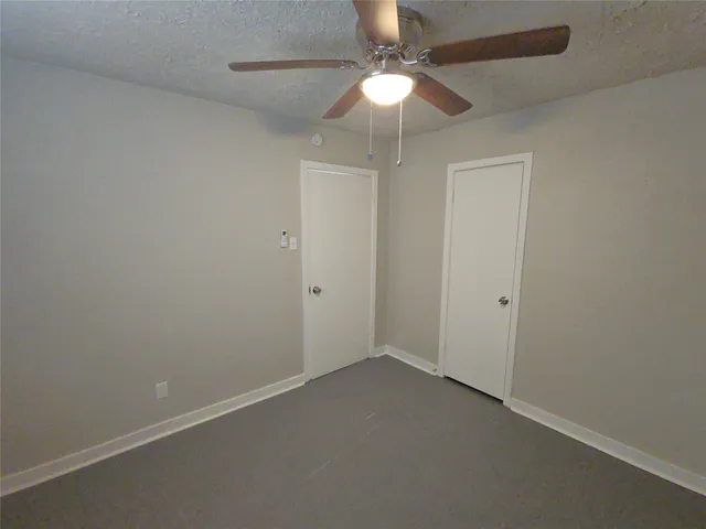 an empty room with a fan & a ceiling fan