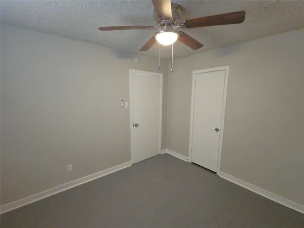 an empty room with a fan & a ceiling fan