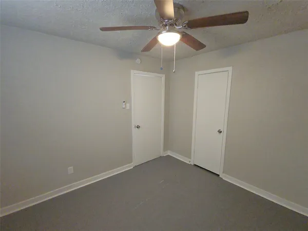 an empty room with a fan & a ceiling fan
