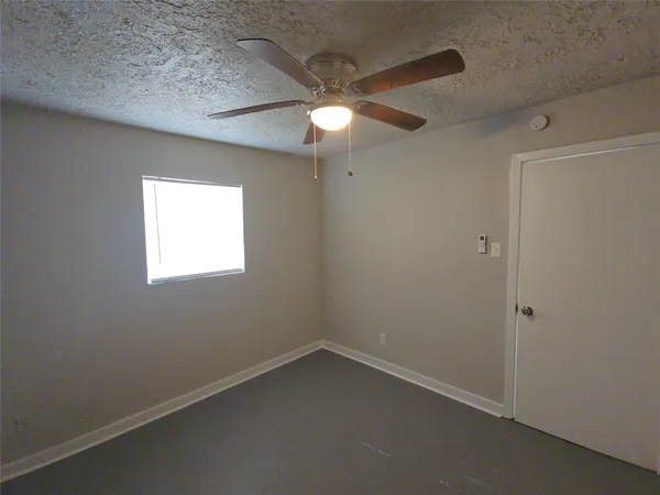 an empty room with a ceiling fan and a window