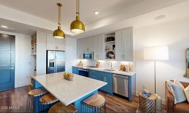 a kitchen with stainless steel appliances granite countertop a sink a stove a refrigerator and island