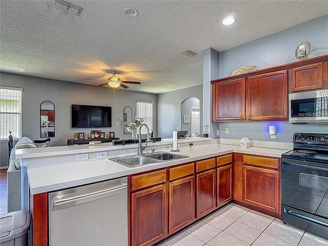 a kitchen with stainless steel appliances kitchen island granite countertop a refrigerator a stove top oven a sink dishwasher and dining table with wooden floor